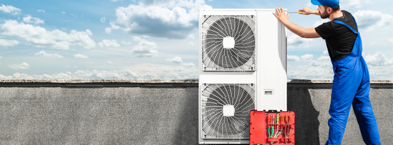 Smart Centreville technician servicing a rooftop HVAC condenser unit under a blue sky